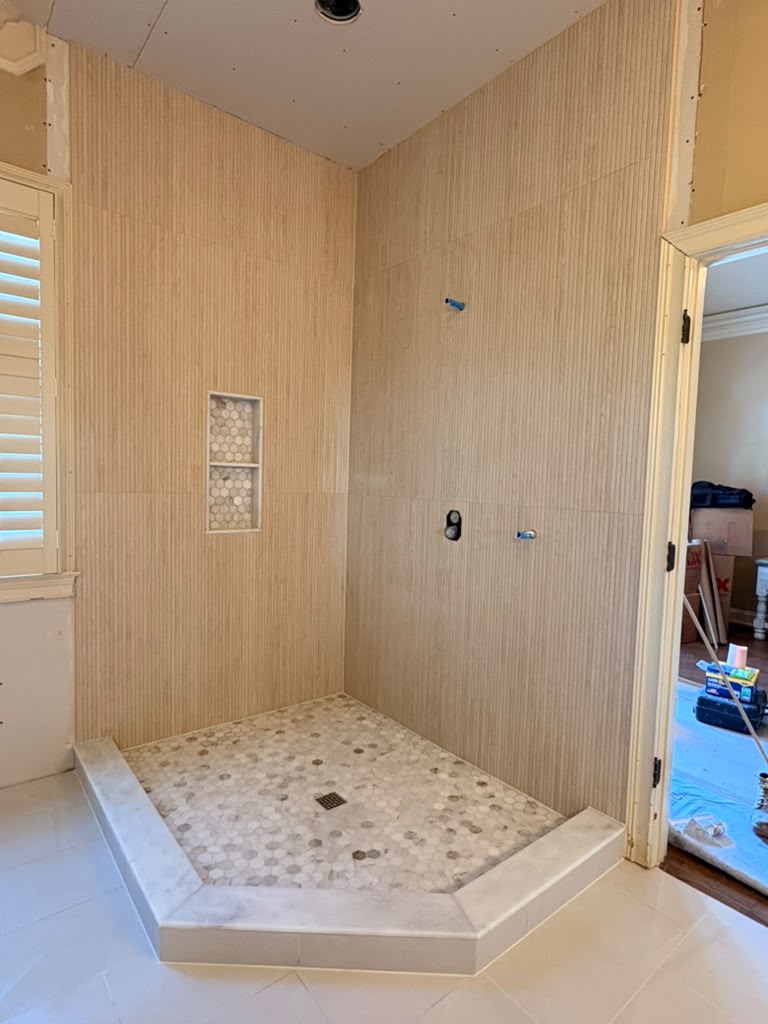 Finished walk-in shower with wood-look wall tile and pebble floor by Daon Construction