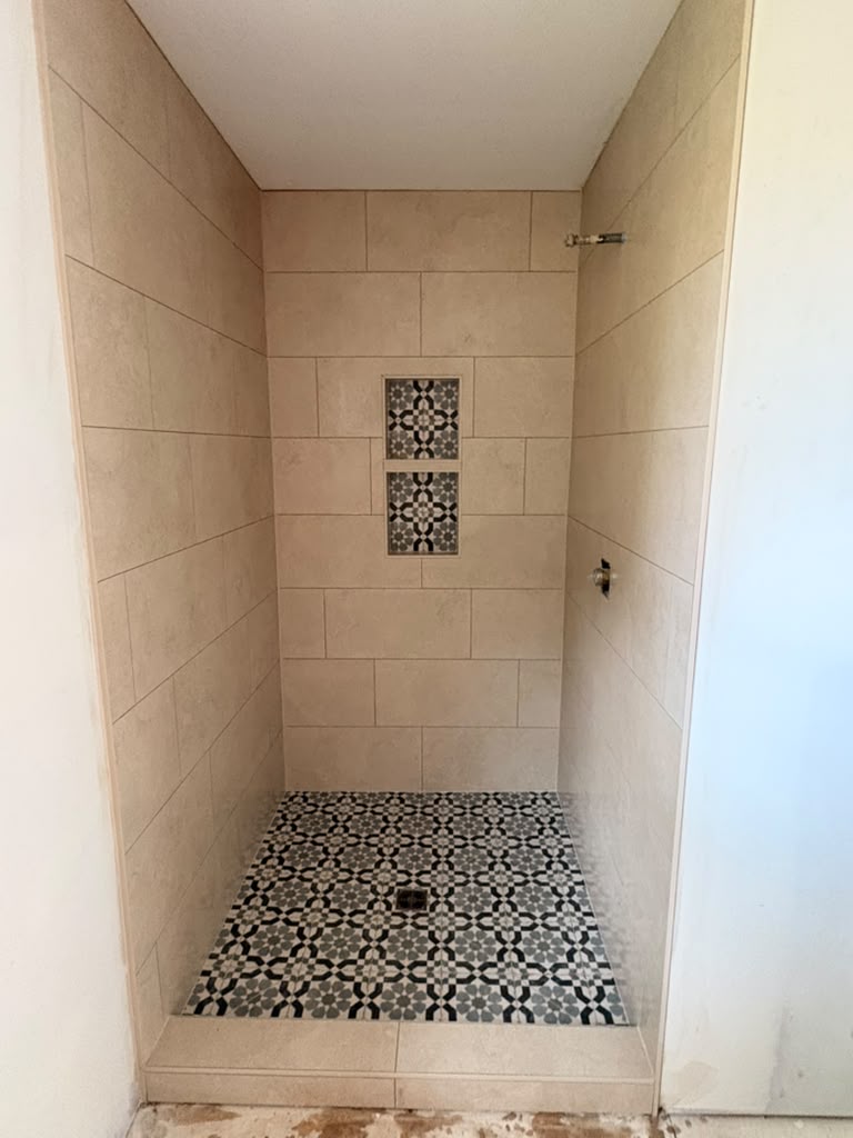 Shower with patterned mosaic floor and tiled niches